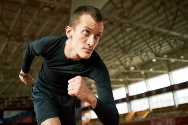 Motivasyonel portre genç sporcunun koşu parkuru modern kapalı stadyumda başlatmak hazır