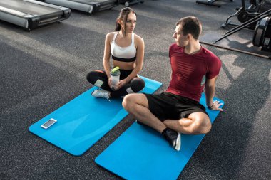 Mola paspaslar modern spor salonunda yoga yaparken genç sportif çift portresi yüksek açı