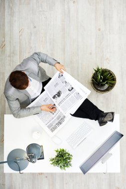 Ofis Masası üzerinde tanınmayan genç işadamı ile otururken ilgi ile gazetede doğrudan yukarıdaki görünümünü bacaklar