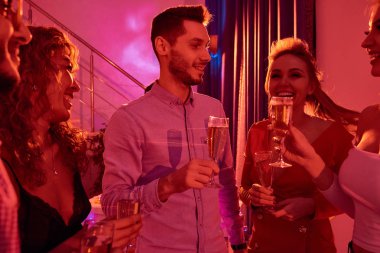 Güzel genç kadınlarla çevrili ve mutlu bir şekilde ev partisi sırasında şampanya yudumlarken sohbet yakışıklı adam portresi