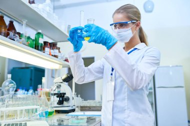 Test tüpleri kimyasallar tıbbi laboratuvar, kopya alanı ders çalışma koruyucu maskeyle çok kadın bilim adamı portresi