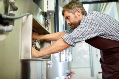Önlük dönüm kulp ekipman endüstriyel makine fabrikası dükkanında tamir ederken bira bira deneyimli teknisyen konsantre