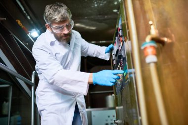 Ciddi konsantre yakışıklı orta yaşlı brewer zanaat bira ekipman ayarlarken fermantasyon tank programı seçme önlük içinde