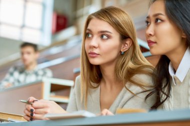 Sınıf için kopya alanı'modern Üniversitesi konferans salonunda diğer öğrencileri arasında oturan ve dinleme iki güzel genç kadın portresi