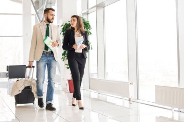 Holding uçak biletleri ve modern Havaalanı bir geçit yürüme çanta güzel modern çift tam uzunlukta portresi