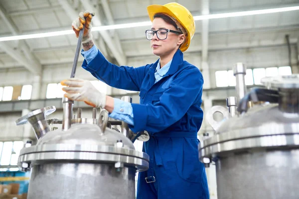 近代的な工場の機器の設定で制服とヘルメットを身に着けている現代の若い女性の肖像画 — ストック写真