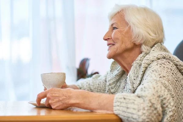 Вид Веселую Пожилую Женщину Трикотажном Свитере Наслаждающуюся Ароматным Кофе Сидя — стоковое фото