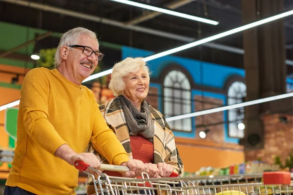 Portret Van Vrolijke Senior Paar Boodschappen Supermarkt Winkelwagentje Samen Trekken — Stockfoto