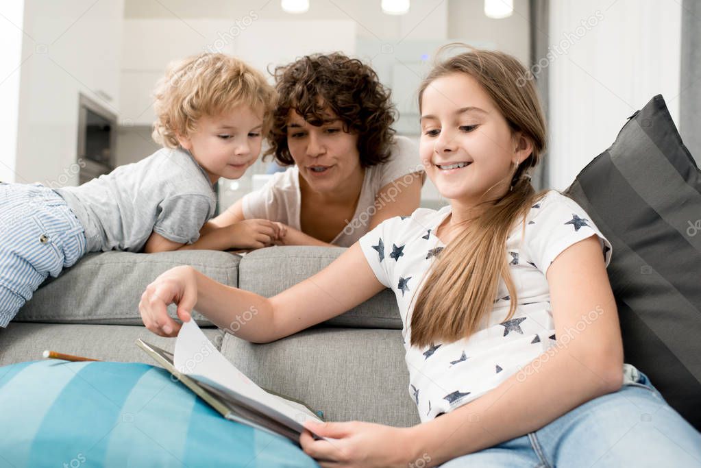 Portrait of young mother spending time at home with two children, helping teenage girl with homework