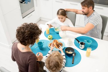 Sabah rahat mutfakta akşam yemeği masada evde kahvaltı keyfi iki çocuklu mutlu genç aile portresi yüksek açı oturan