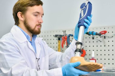 Genç prosthetist için kalite kontrol ve ayarlama modern laboratuarda çalışırken yapım protez bacak tutan portresi