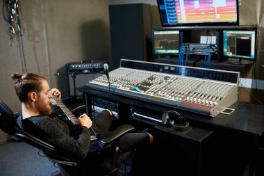 Koltukta, rahatlatıcı ve kayıt stüdyosunda Ses mühendisi olarak çalışırken elektro gitar çalmak yetenekli hipster genç müzisyen