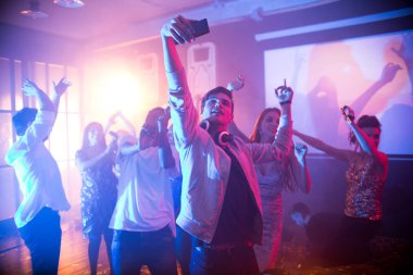 Kalabalık gece kulübünde dans ve parti, dans pistinde selfie alarak yakışıklı genç odaklanmak zevk trendy gençlerin
