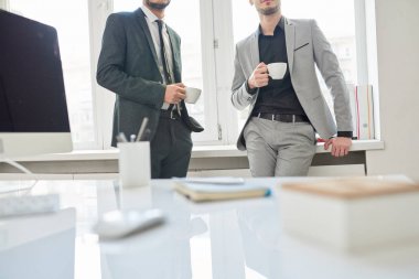 Kahve molası, bardak tutan ve modern ofis penceresinde eğilerek iki başarılı iş adamları orta kesit portresi