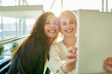 Modern alışveriş merkezinde büyüleyici gülümsüyor selfie birbirlerinin tadını çıkarırken dijital tablet alarak ile neşeli genç arkadaşlar şirket