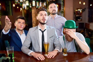 Ragbi maçı izlerken ve, onlardan biri akşam harcama yaparken bira içme sakallı erkekler hoşnutsuzluk el gözlerle kapsayan cin giyinen