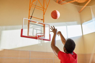 Yalnız sahada eğitimi sırasında sepete topu atma Afrikalı-Amerikalı basketbolcu arka görünümü