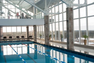 İç cam duvarlı geniş modern bir sağlıklı yaşam merkezi: Yüzme Havuzu ve şezlonglar birinci katta, ziyaretçileri ile fitness salonu saniyelik bir