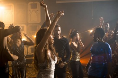 Gençlerin grup eğleniyor gece kulübünde, güzel kızlar dumanlı Club dans pistinde dans pırıltılı giysiler giyiyor trendy