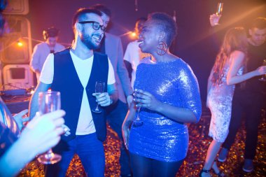 Genç çok etnik gruptan oluşan grup zevk Resepsiyon parti millet, tombul Afrikalı-Amerikalı kadın giyiyor kısa parlak elbise ve içki şampanya sakallı Asya adam konuşurken odaklanmak