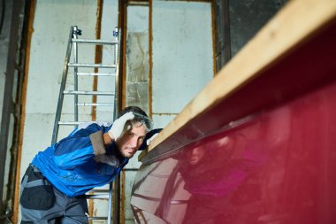 Portrait of handsome worker checking paint coating while repairing boat in yacht workshop clipart