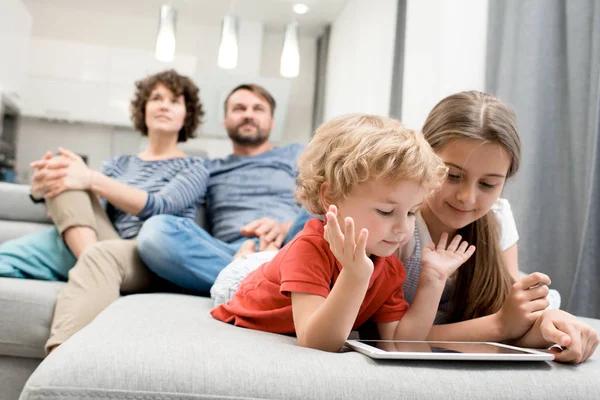 Linda Niña Hermano Rizado Tumbado Sofá Acogedor Jugando Tableta Digital — Foto de Stock