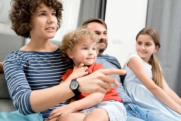 リビング ルームでソファの上に座って 映画を議論するテレビを見て 人の子供と幸せな若い家庭の肖像画 — ストック写真