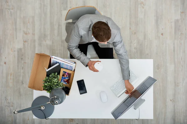 Tanınmayan Yöneticisi görünümünü el Ofis Masası oturma ve kutusu ile onun aidiyet ayakta onu yanında modern bilgisayar açma kahve fincan kağıt üstünde