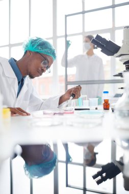Laboratuvarda çalışan Afro-Amerikan bir adamın portresi deney örneklerini tıbbi araştırmalar için petri kabında hazırlıyor.