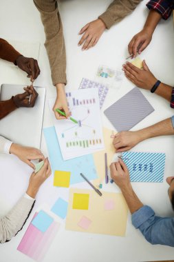 Grup projesini tartışan ve beyin fırtınası yaparken renkli grafiklere işaret eden tanınmamış gençlerin bakış açısının üzerinde, alanı kopyala