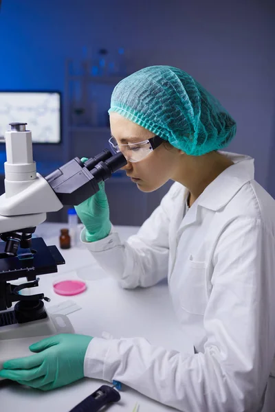 年轻女性在实验室进行医学研究时显微镜下的侧视图画像 — 图库照片