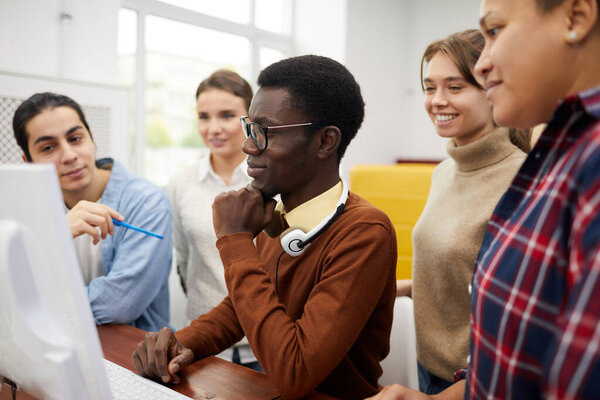 Side view at multi-ethnic group of students using computer while researching for team project in library