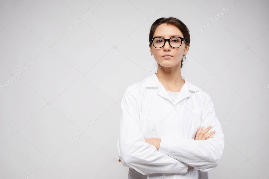 Waist up portrait of confident female scientist standing with arms crossed while posing against white background, copy space