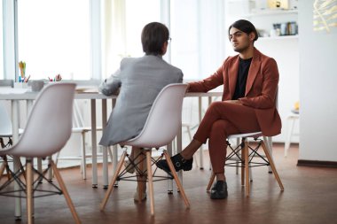 Çağdaş iki iş adamına tam boy görünümü pencereye karşı toplantı masasında oturmayı tartışan, boşluğu kopyalayan