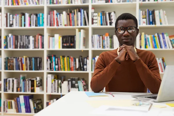 Portret Młodego Afroamerykanina Patrzącego Kamerę Podczas Pozowania Bibliotece Koledżu Siedzącego — Zdjęcie stockowe