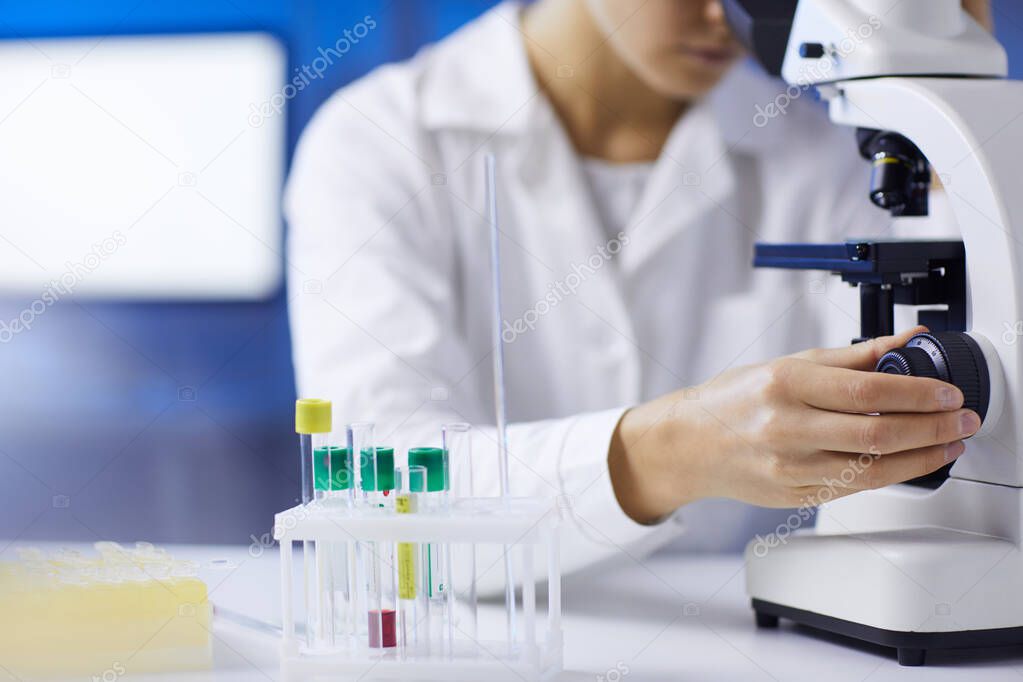 Close up of unrecognizable female scientist setting up microscope while doing medical research in laboratory, copy space