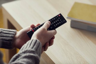 Evdeki TV izlerken uzaktan kumandayı elinde tutan erkeklerin yüksek açılı yakın çekimi, boşluğu kopyala