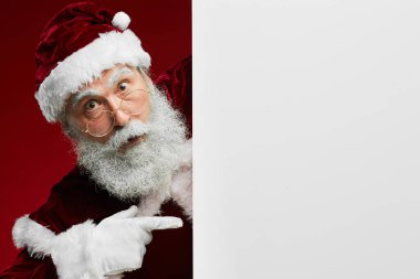 Şaşırmış Noel Baba 'nın portresi kameraya bakarken boş beyaz işareti gösteriyor, boşluğu kopyala