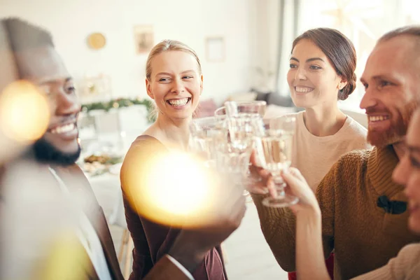 在圣诞派对上 一群优雅的朋友一边举杯庆祝 一边看着两个女人开心地笑着 — 图库照片
