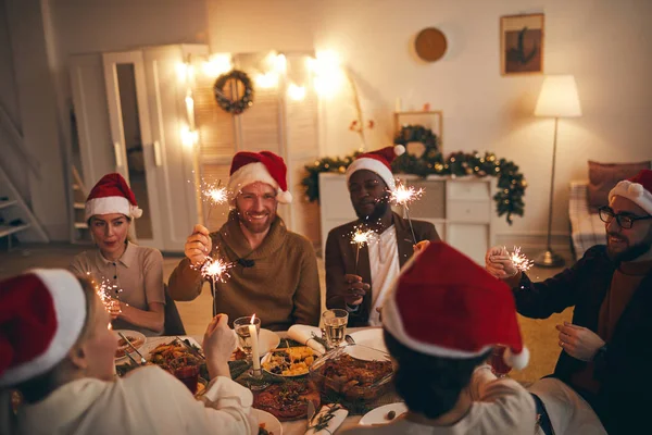 Wieloetniczna Grupa Ludzi Trzymająca Błyszczące Światła Podczas Świątecznej Kolacji Domu — Zdjęcie stockowe