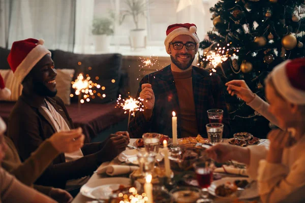 Group Cheerful People Holding Sparklers While Enjoying Christmas Dinner Home — Stock Photo, Image
