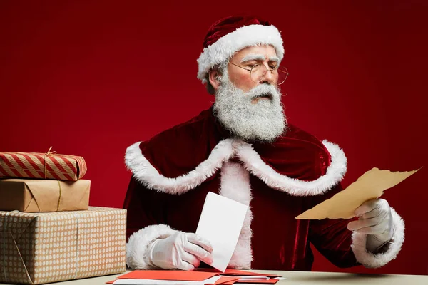 Klasik Noel Baba Portresi Masada Oturmuş Kırmızı Arka Planda Noel — Stok fotoğraf