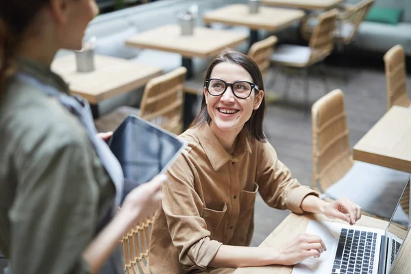 年轻女性在咖啡店工作时看着女服务员微笑的高角肖像 复制空间 — 图库照片
