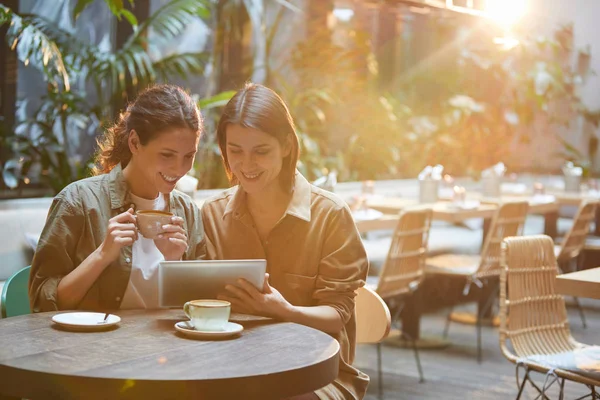 Retrato Dos Mujeres Contemporáneas Mirando Pantalla Tableta Mientras Disfrutan Reunión —  Fotos de Stock