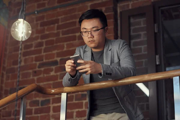 Χαμηλή Γωνία Πορτρέτο Του Νεαρού Ασιάτη Επιχειρηματία Χρησιμοποιώντας Smartphone Στέκεται — Φωτογραφία Αρχείου