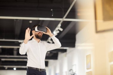 Sanat galerisindeki sergi sırasında VR giysileri giyen modern sakallı adamın belden yukarı portresi.