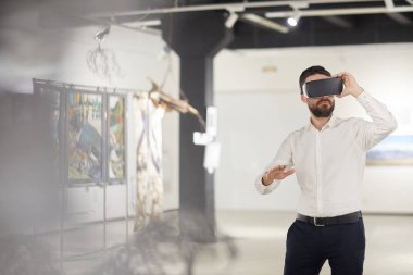 Sanat galerisindeki sergi sırasında VR giysileri giyen modern sakallı adamın portresi.