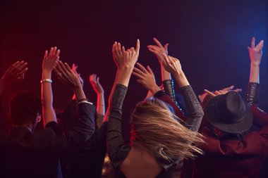 Dumanlı gece kulübünde eğlenirken zıplayan ve el kaldıran gençlerin arka planı, kopyalama alanı