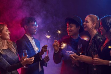 Smoky Night Club 'da Noel partisinde havai fişek yakan çok ırklı bir grup zarif genç.