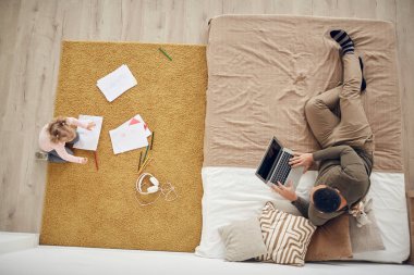 Küçük bir kızın rahat yatak odasında babasıyla oynadığı arka planda dizüstü bilgisayar kullanarak, boşluğu kopyalayarak...